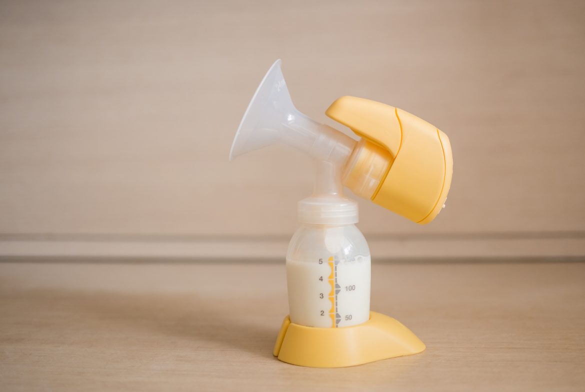 The electric breast pump is on the table in the kitchen. Breast pump with milk. Give expressed breast milk. Breast care for a young mother Laktator elektryczny czy ręczny? Rozwiewamy wątpliwości
